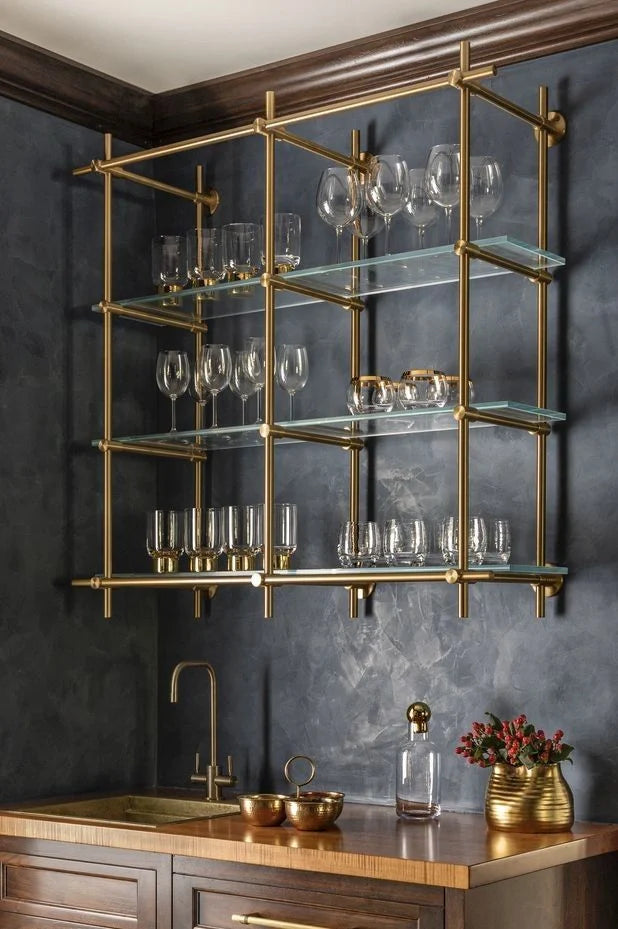 Brass shelving installed behind a bar, displaying bottles and glassware on sleek, polished metal shelves that add a warm, upscale touch to the space.