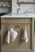 rod mounted on a kitchen wall used as  a bar for dishclothes and towels