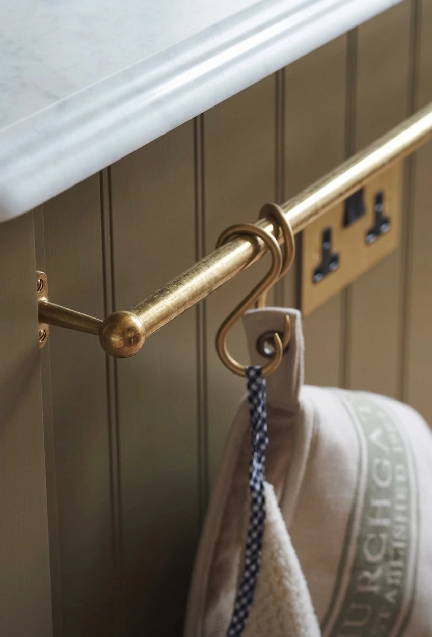 rod made of brass in aged brass finish used as a pot and pans rack installed on a white wall 