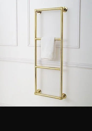 Gold-finished metal towel rail mounted on a white paneled wall, with a white towel draped over the middle bar.