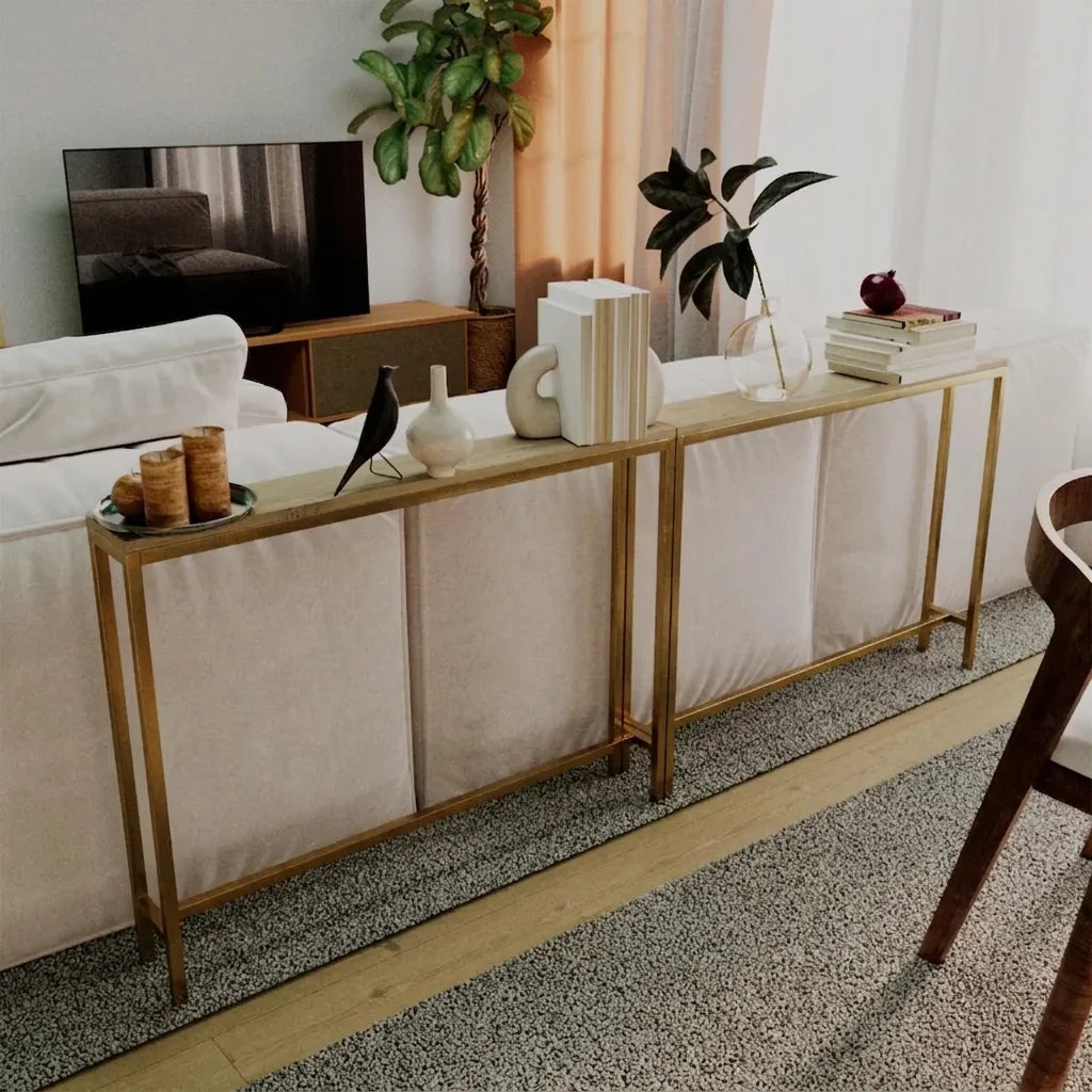 A modern console table with a gold metal frame and cream fabric panels, styled in a bright living room next to a white sofa.