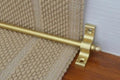 Stair rod ona beige rug and rug holder with a polished finish, designed to securely hold stair runners in place while adding a decorative and elegant touch to the staircase.