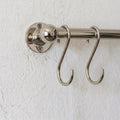 rod made of brass in nickel finish used as a pot and pans rack installed on a white wall 