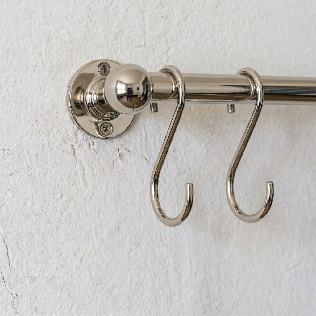 rod made of brass in nickel finish used as a pot and pans rack installed on a white wall 