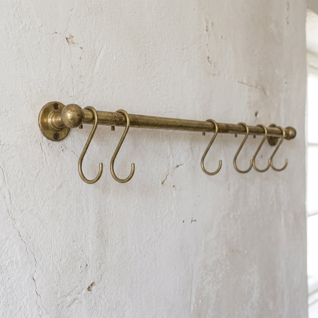 rod made of brass in aged brass finish used as a pot and pans rack installed on a white wall 