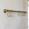 rod made of brass in aged brass finish used as a pot and pans rack installed on a white wall 