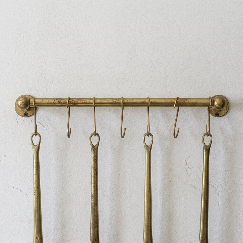 rod made of brass in aged brass finish used as a pot and pans rack installed on a white wall 