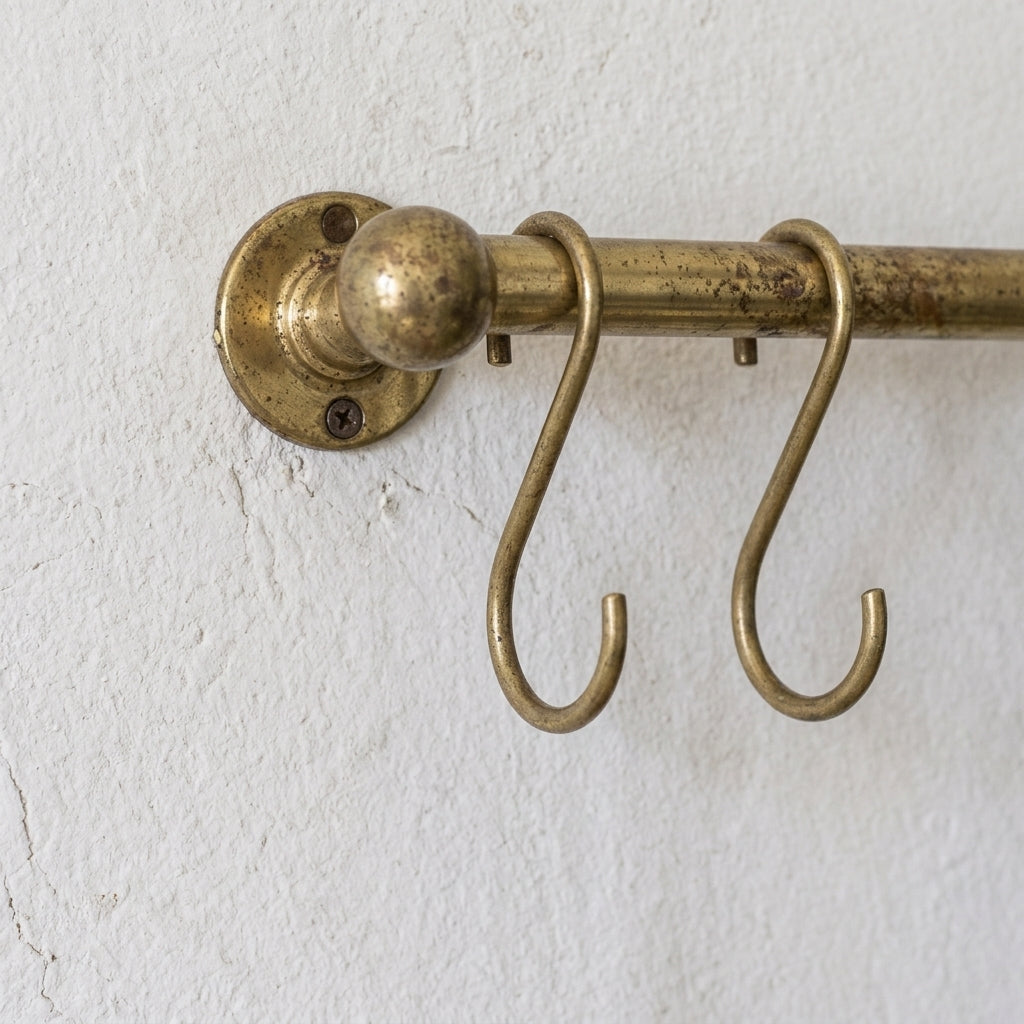 rod made of brass in aged brass finish used as a pot and pans rack installed on a white wall 