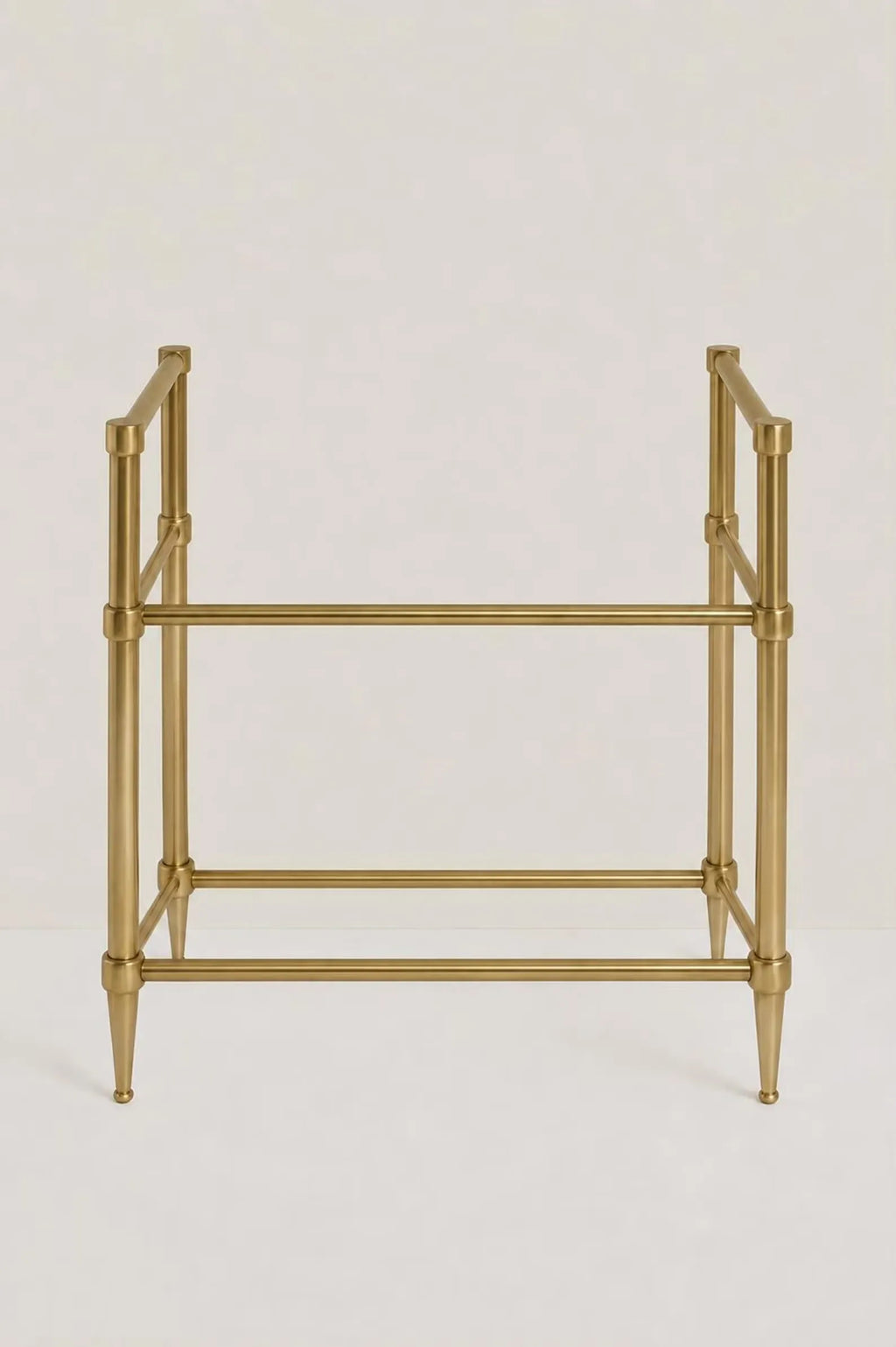 A gold-finished metal stand with a geometric frame design, featuring four legs with tapered ends and two horizontal bars, shown against a plain light background.