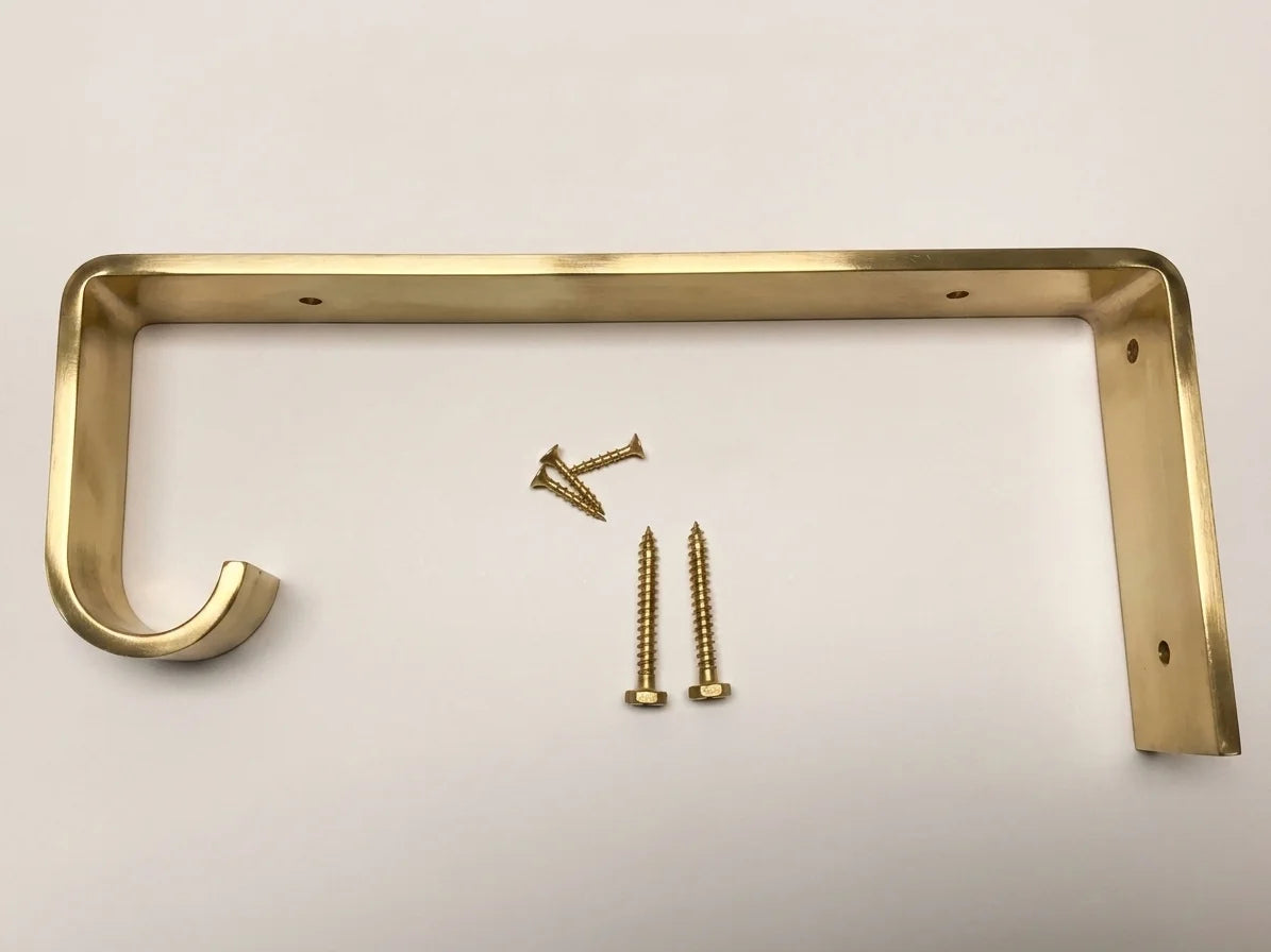 A brass wall hook bracket with two mounting screws, displayed on a clean white background.