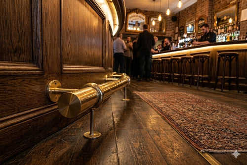 Brass foot rail in a cozy bar with patrons seated at the counter, providing comfort and a stylish, classic touch to the warm and inviting atmosphere.
