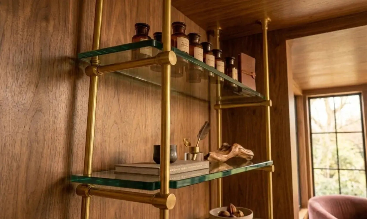 French Bistrot Shelves with brass brackets  in gold  ffinish and glass shelves against a wooden wall.