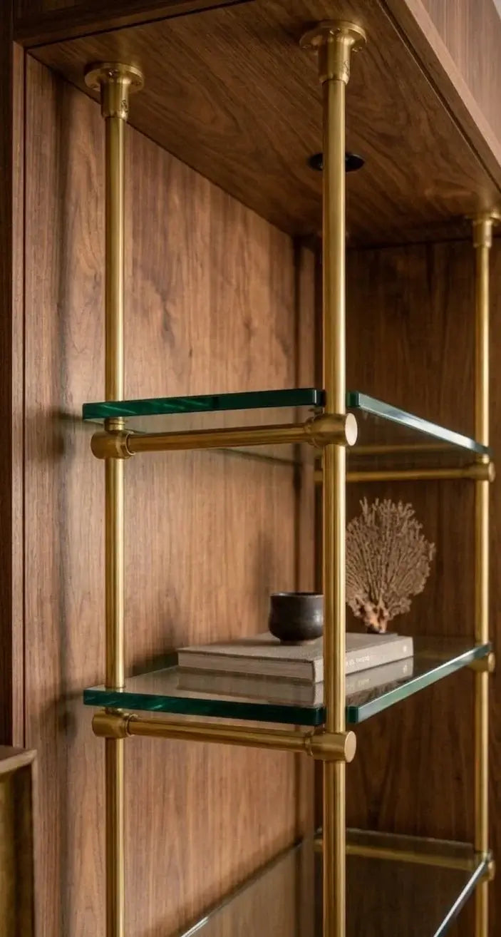 French Bistrot Shelves with brass brackets  in gold  ffinish and glass shelves against a wooden wall.