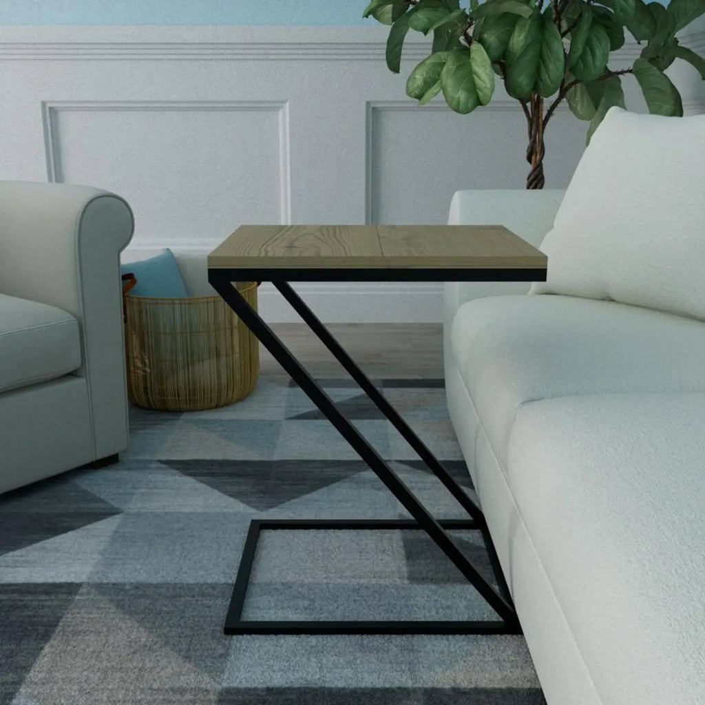 A modern side table with a light wood top and a black metal Z-shaped frame, styled in a living room next to a white sofa on a gray patterned rug.