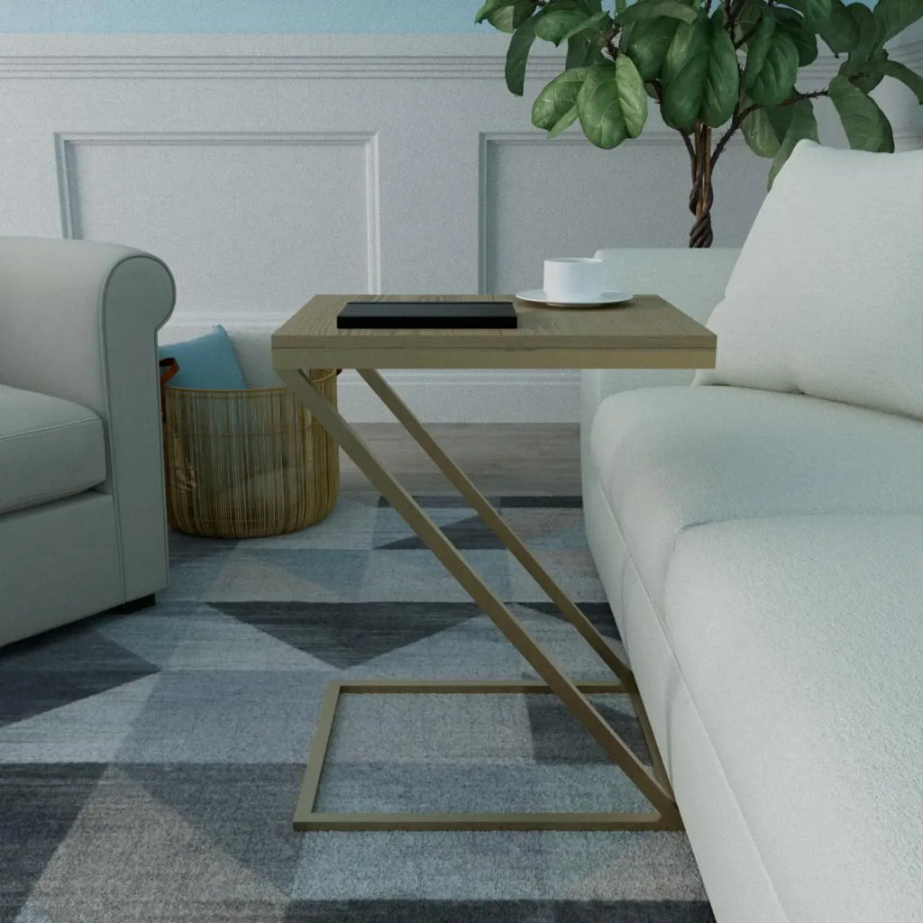 A modern side table with a light wood top and a gold-finished geometric metal frame, styled in a living room next to a white sofa on a gray patterned rug.