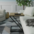 A modern side table with a light wood top and black metal frame, styled in a living room next to a white sofa with a cup of coffee on top.